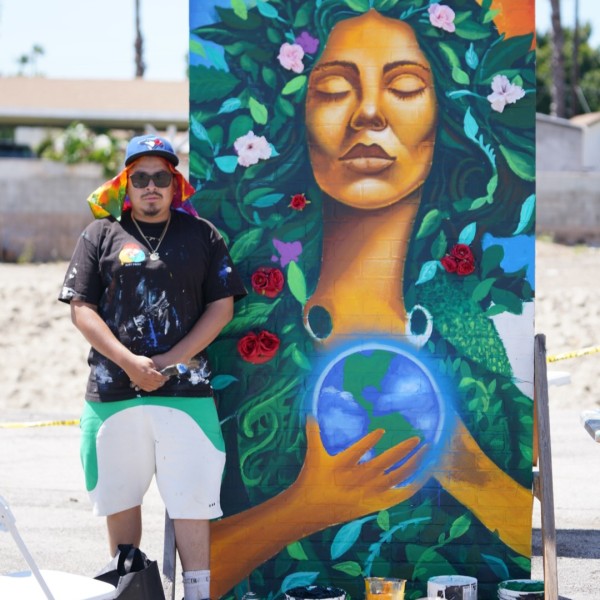 Juan Pablo Reyes aka JP Murals poses next to his mural